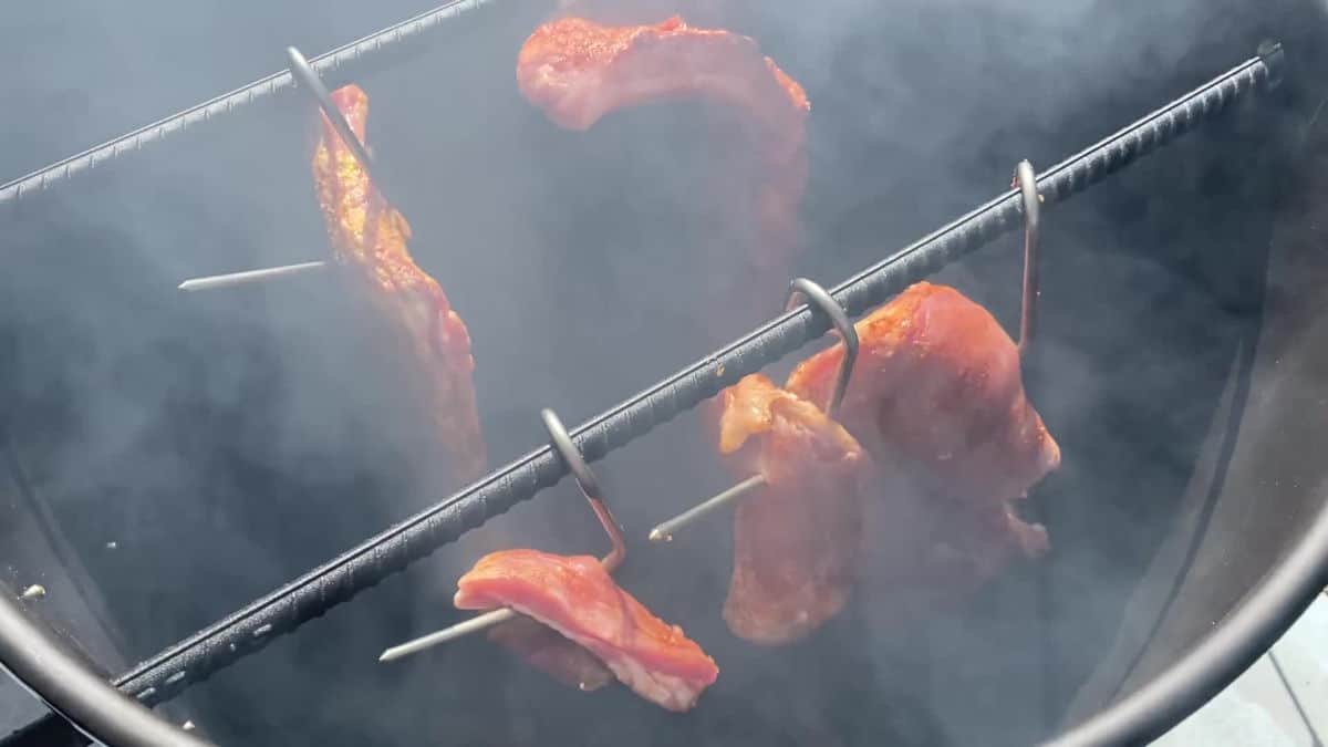 A few racks of ribs smoking inside a pit barrel cooker.