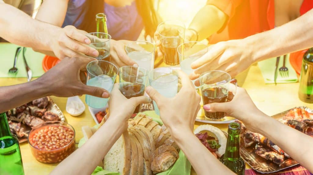 A group of people toasting alcoholic drinks at a barbecue