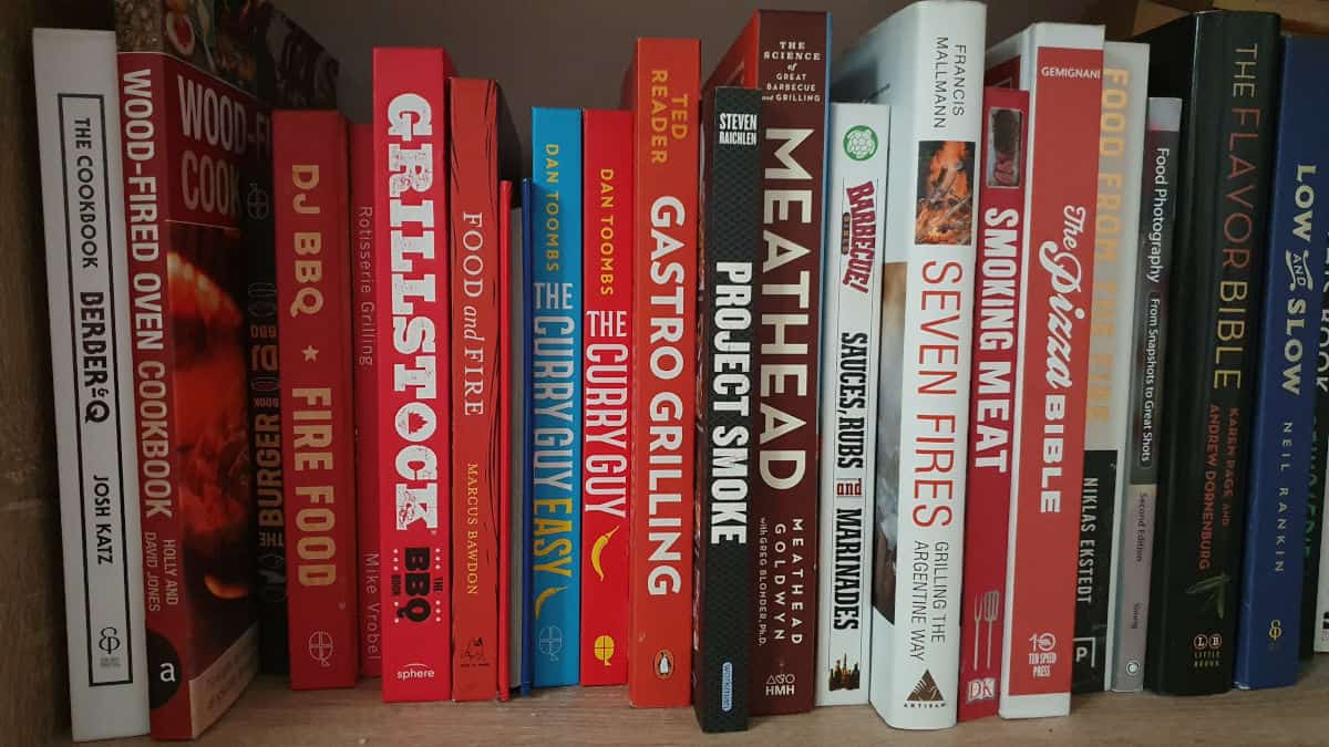 A line of various stood up BBQ cookbooks, looking at the spines