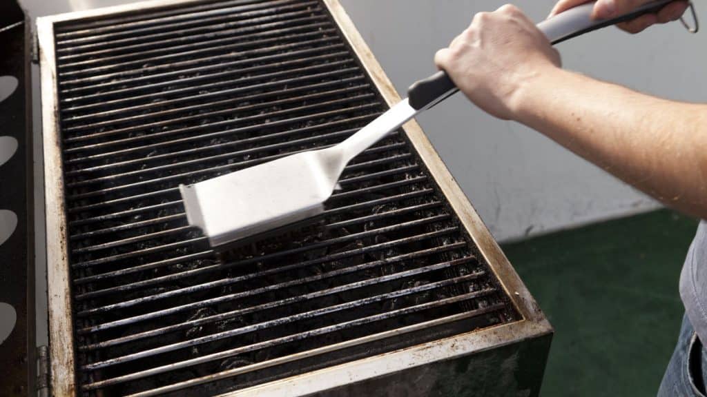 A man scrubbing grill grates with a brush