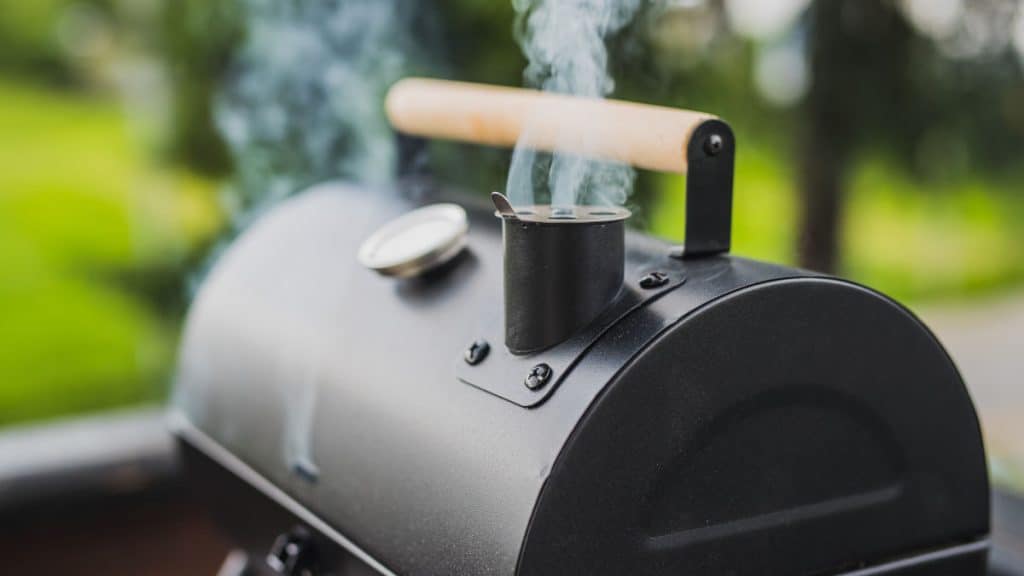 An offset smoker with smoke coming out of the chimney