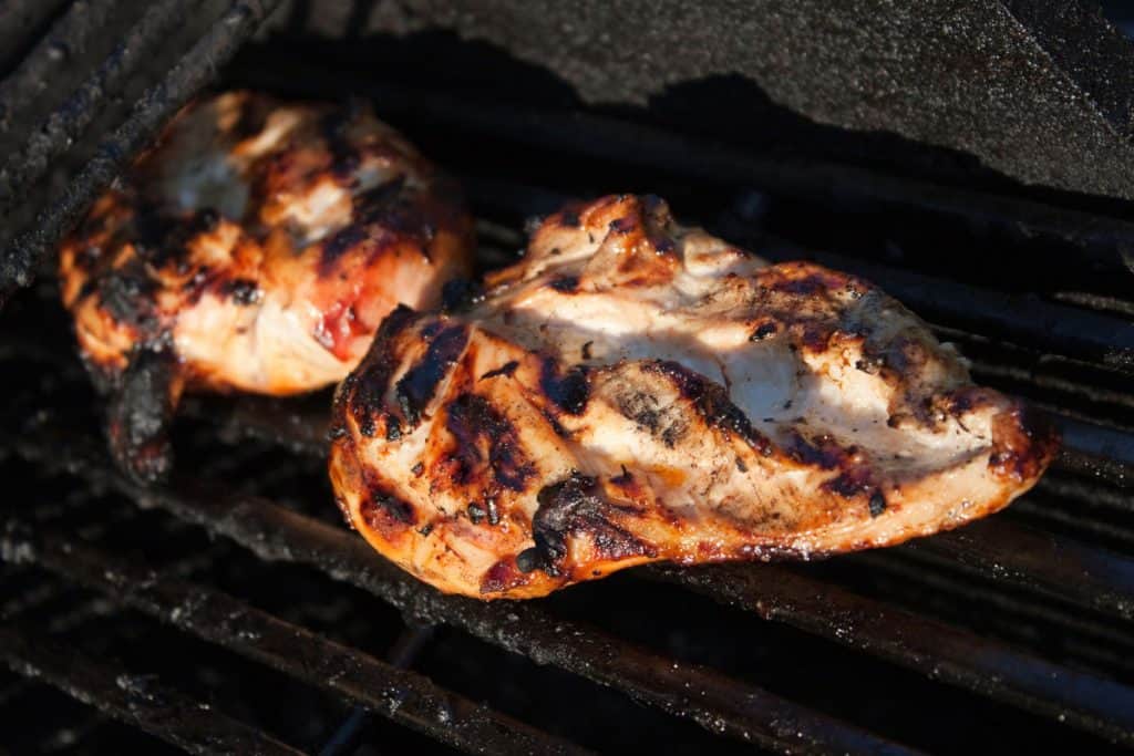 Two pieces of burned chicken breast on a grill