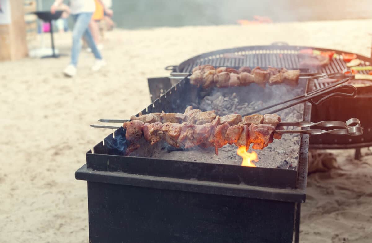 Two charcoal grills on a sandy beach