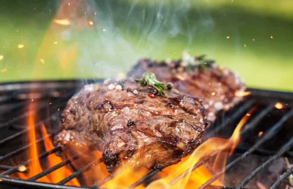Steak being licked with flames while grilling outdoors