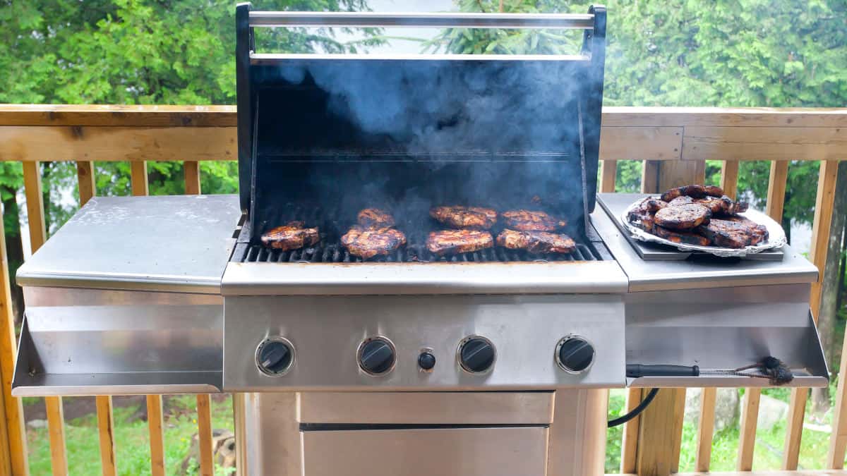 Gas grill with the lid open and burgers on the grate