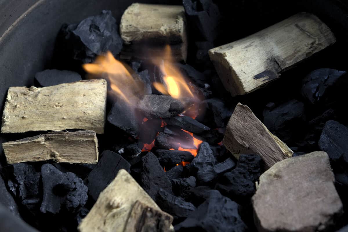 Burning charcoal with wood for smoking meat