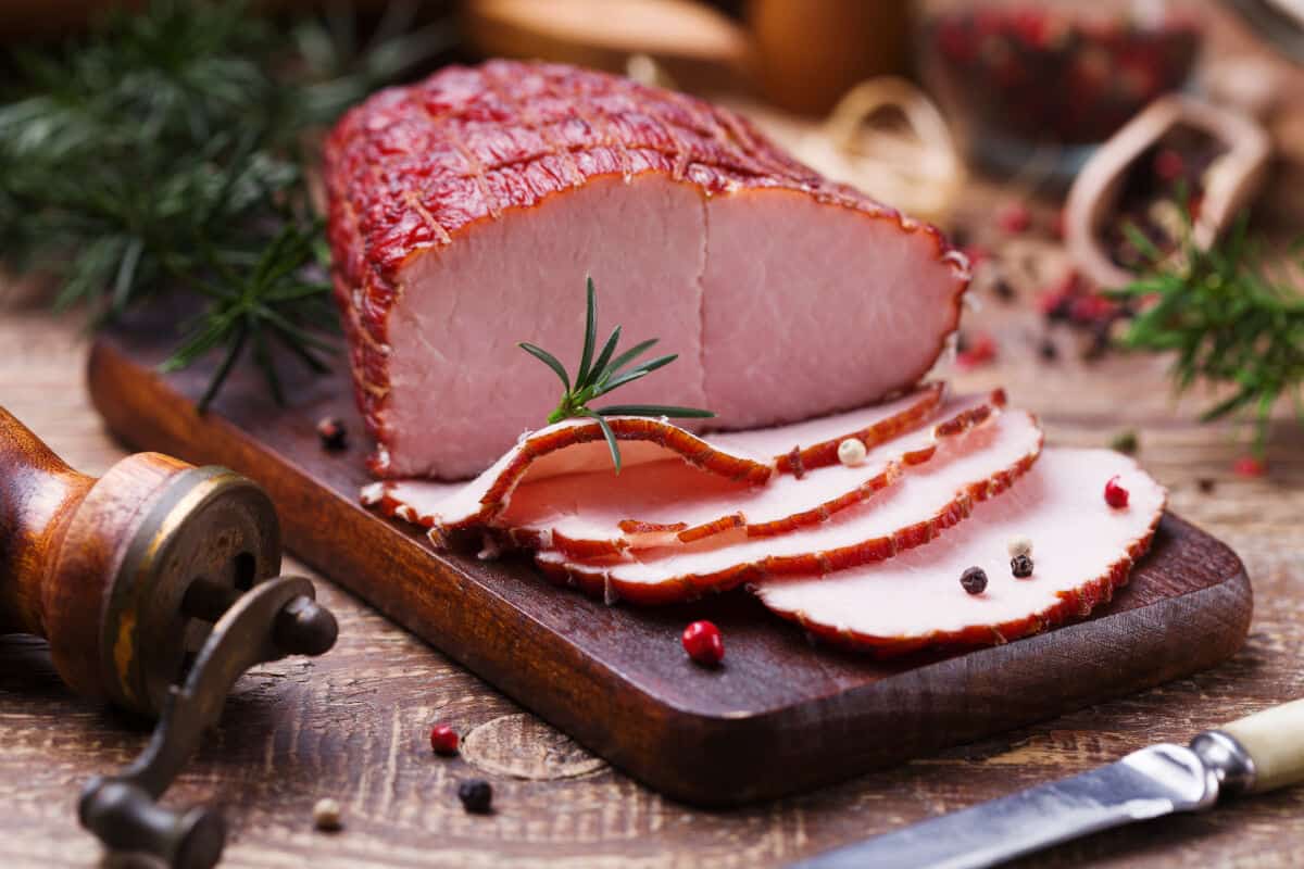 A partially sliced ham on a chopping board