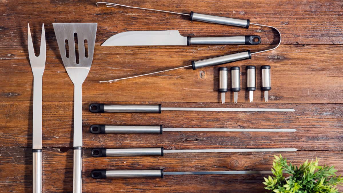 A set of bbq and grilling tools laid out on a wooden table