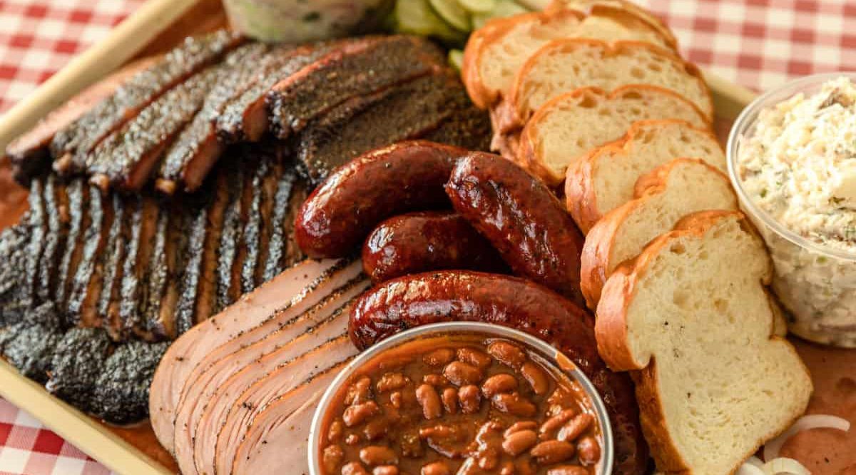 a barbecue platter of mixed meats including brisket, ribs, sausage and sides