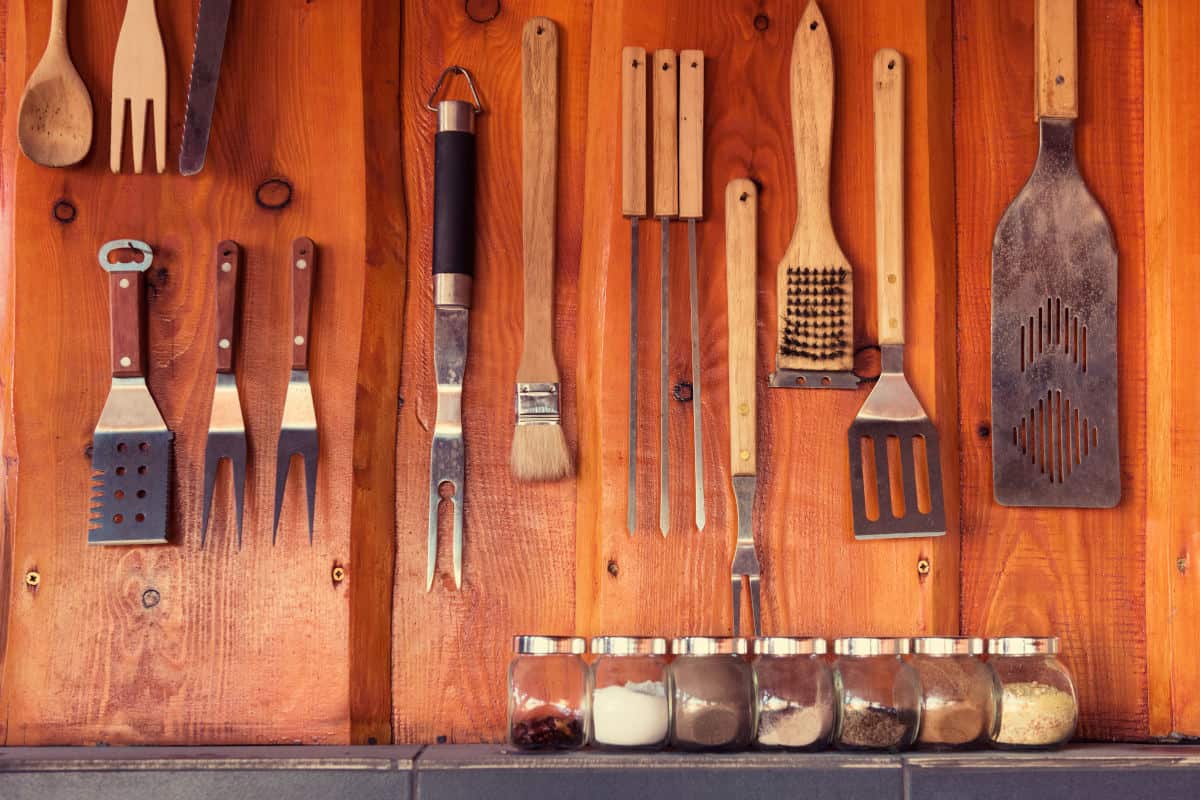 Lots of grill tools hanging on a wooden wall