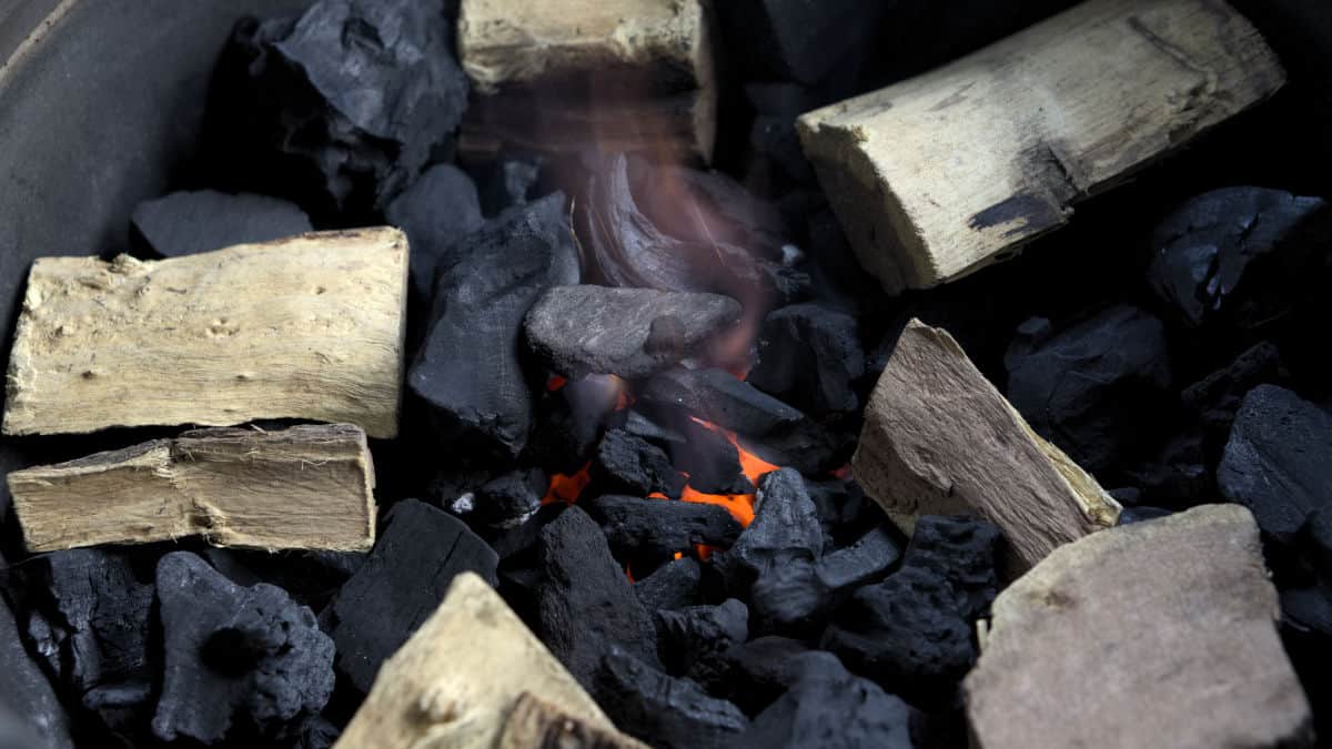 Close up of lit charcoal with smoking wood on top, laid out in a circle