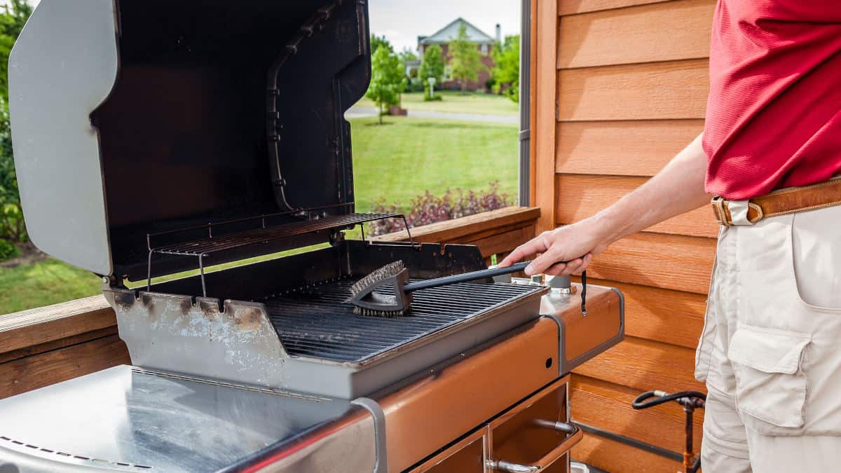 A man cleaning his grill with a grill brush