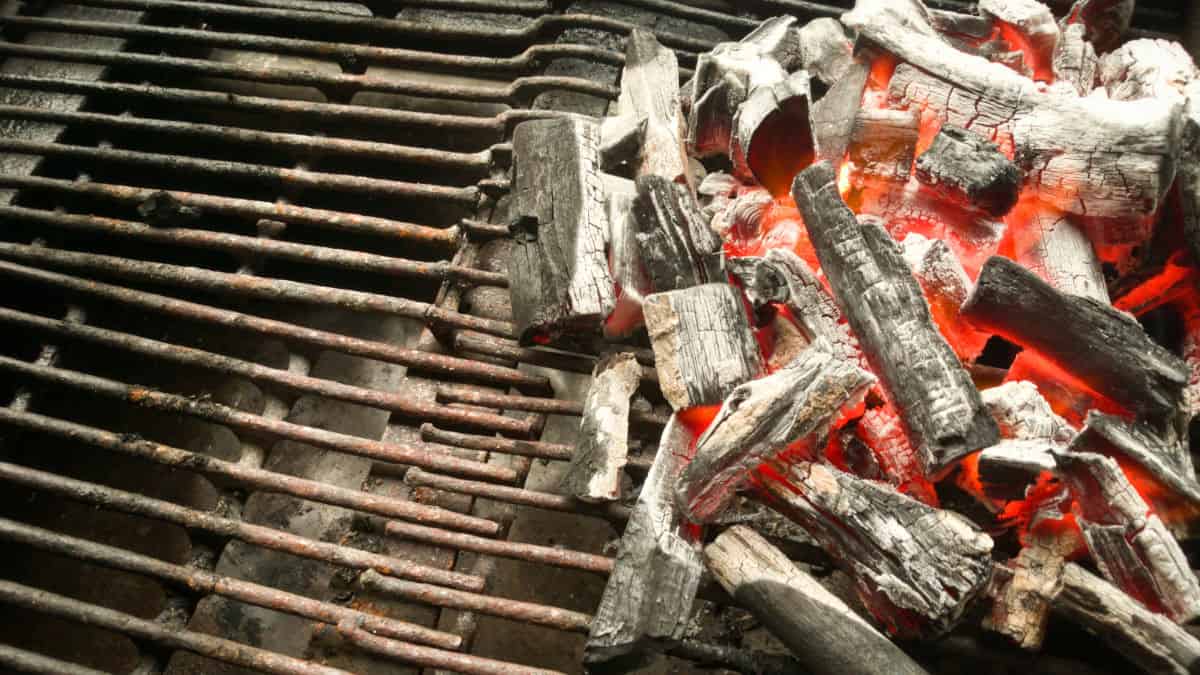 Burning lump charcoal banked up on half a charcoal fire grate