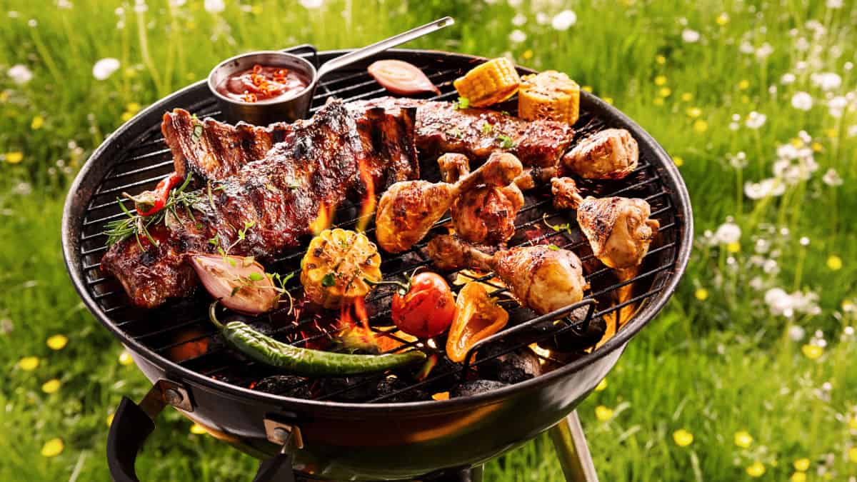 A portable charcoal grill loaded with meat and vegetables