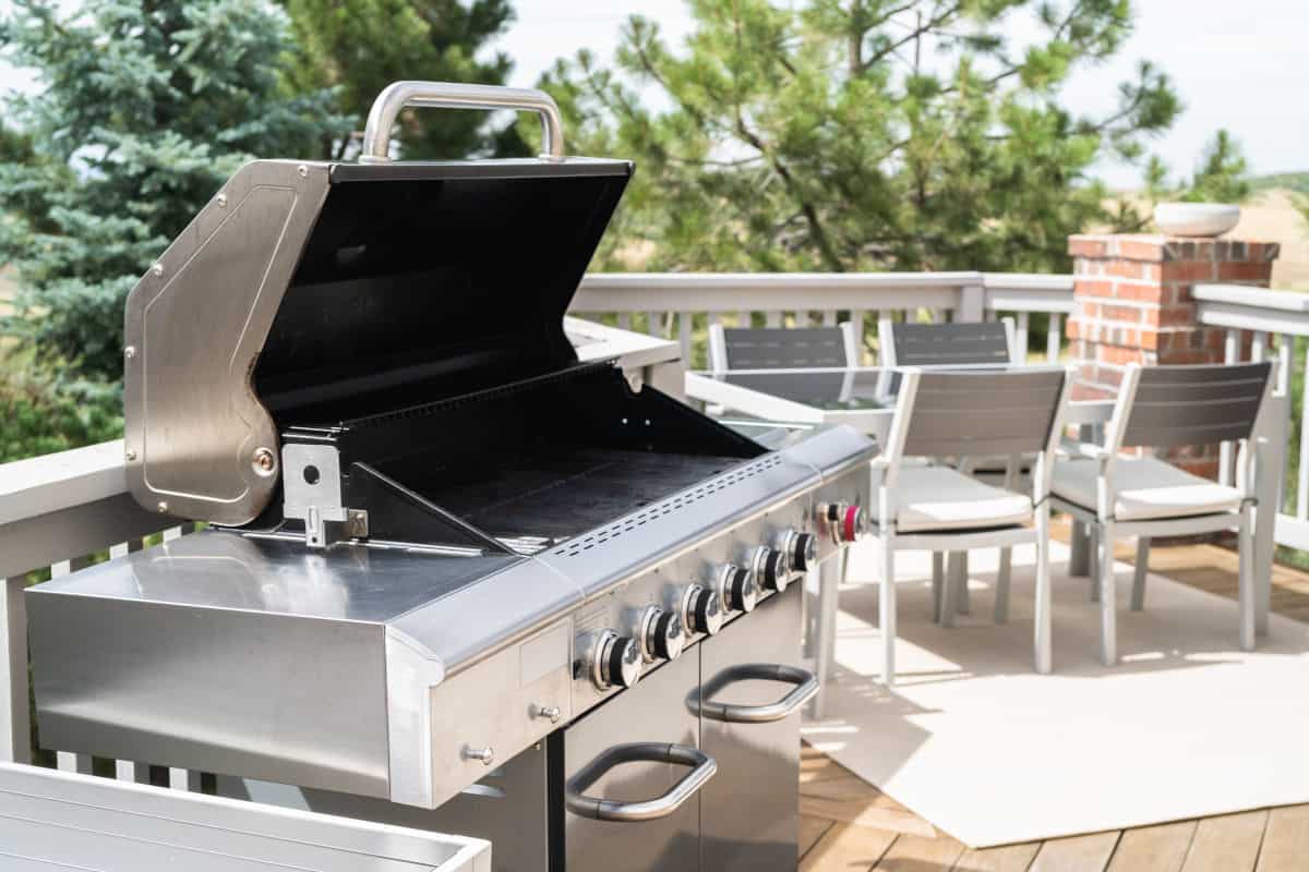 Side view of a gas grill, lid open on a sunny patrio