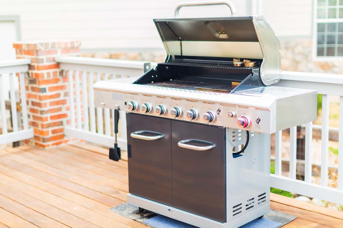 A black and silver gas grill on a wooden decking