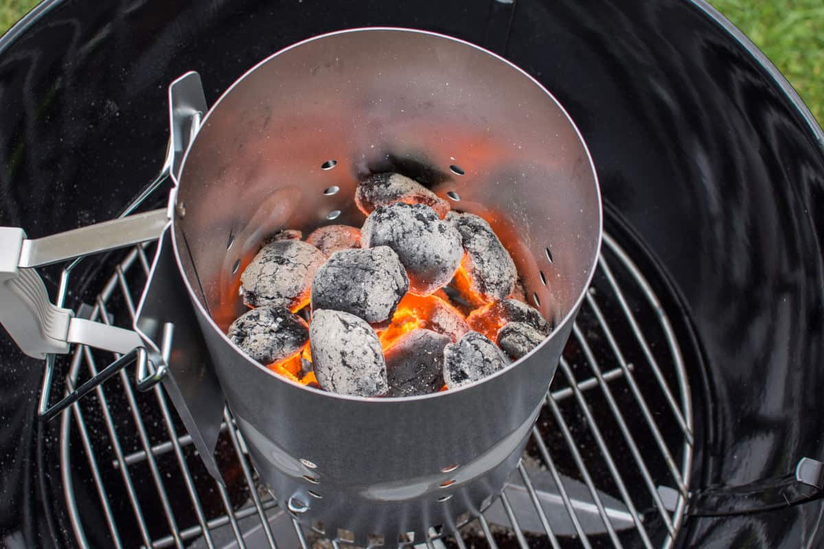 Looking down into a half full charcoal chimney starter with lit coals
