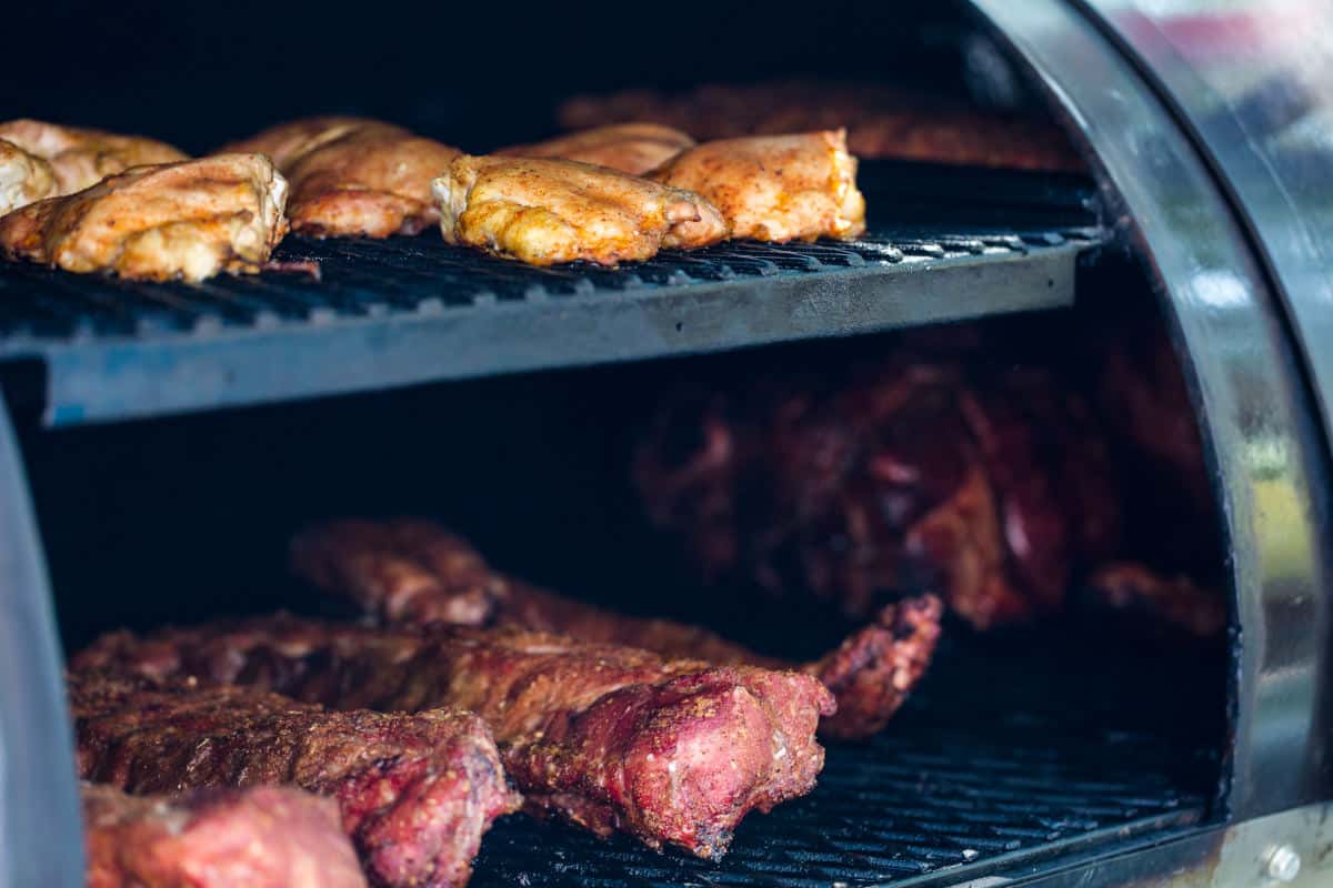 A pellet smoker fully loaded with meat on 2 shelves