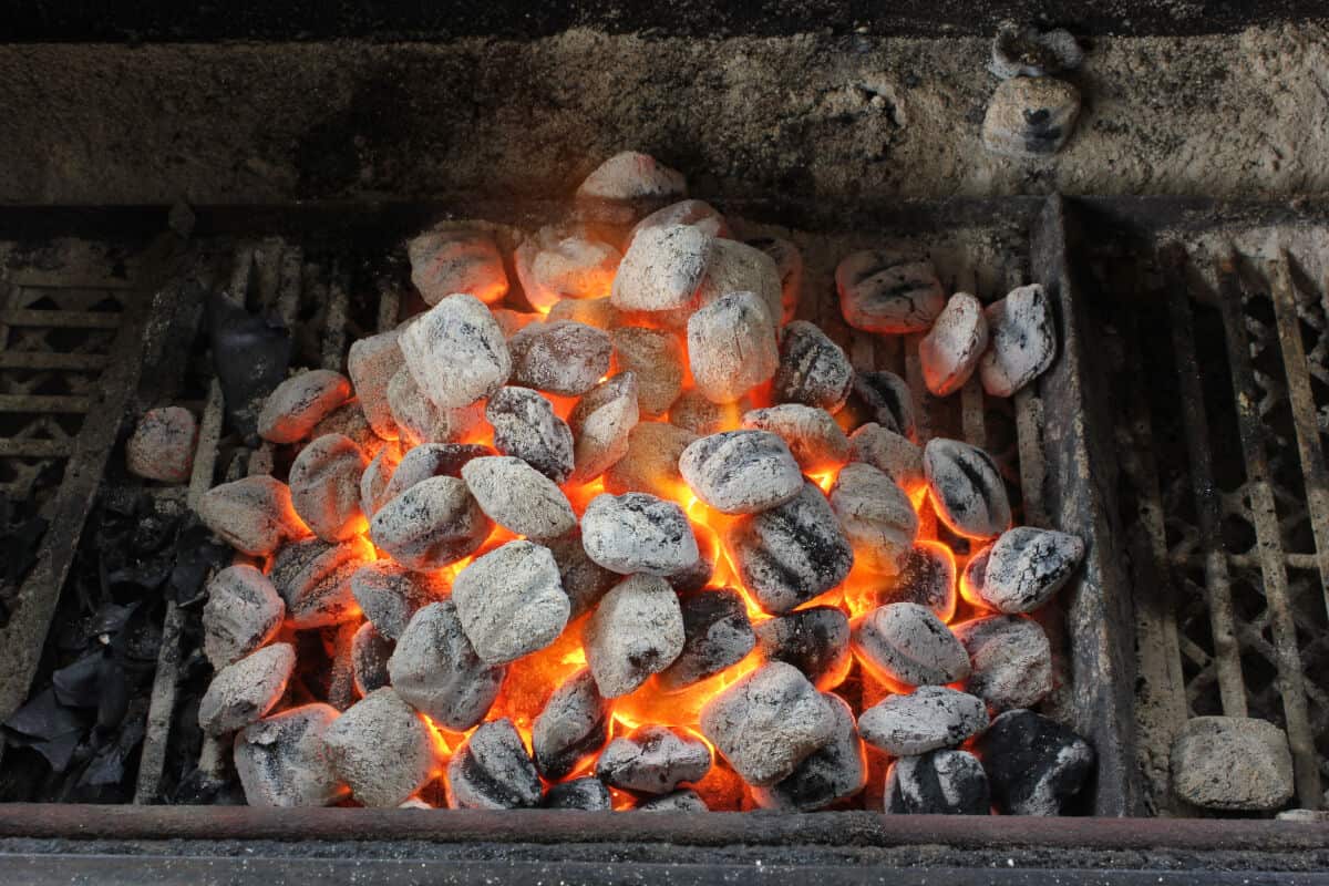 A pile of lit briquettes in a charcoal barbecue