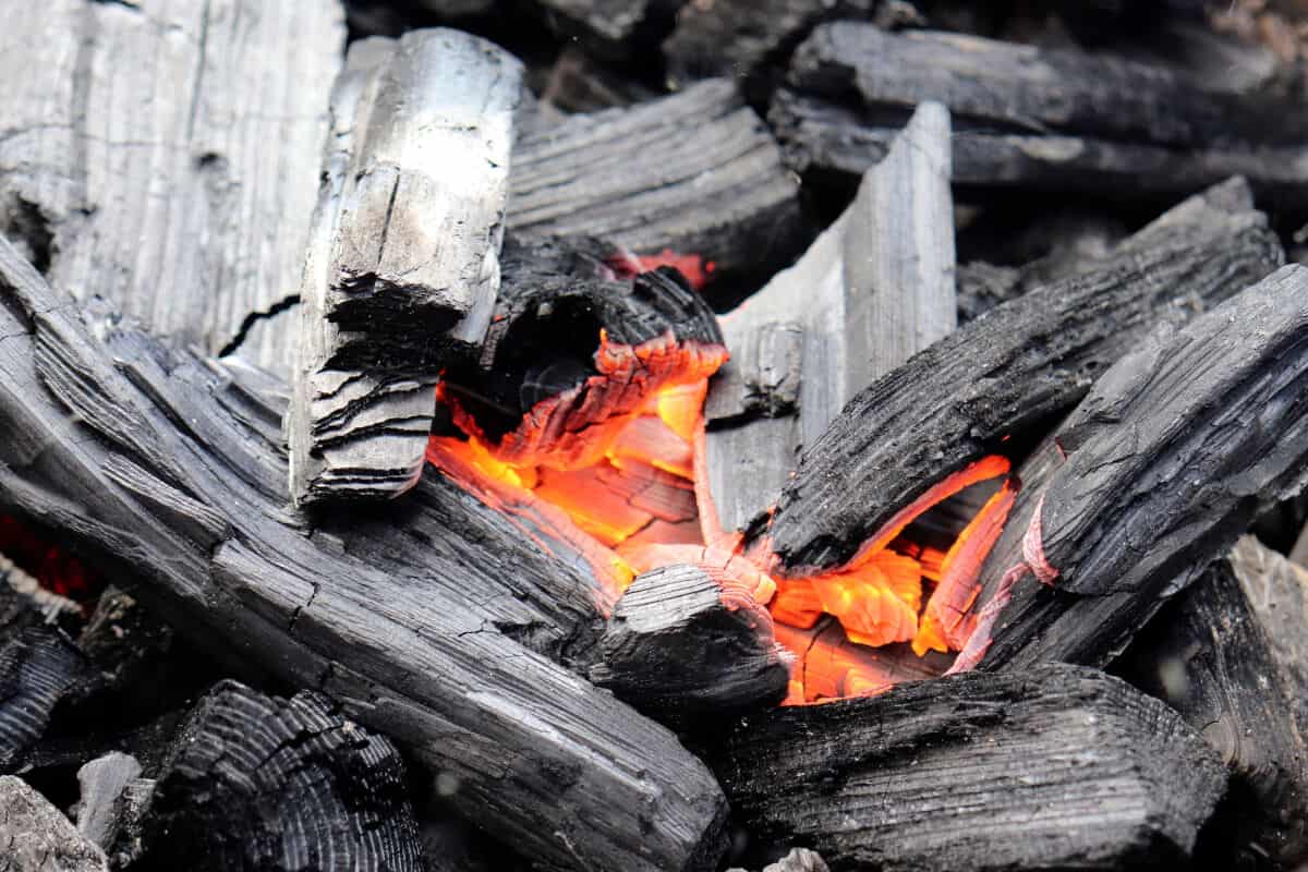 A pile of lumpwood charcoal, that is lit and burning just in the center