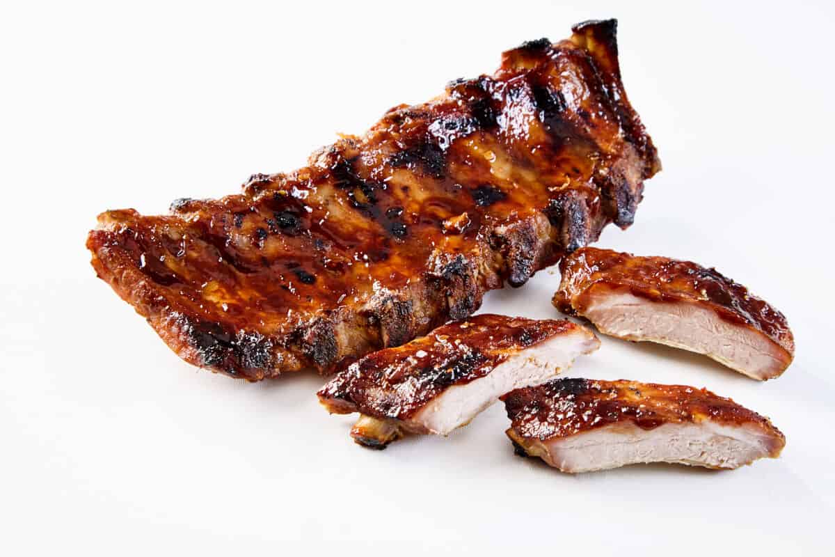 A rack of bbq ribs, with 2 sliced off, isolated on white