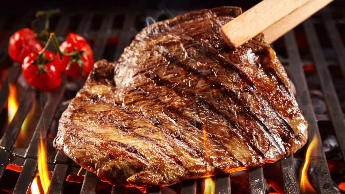 A steak, held up on it's side, being seared on a grill