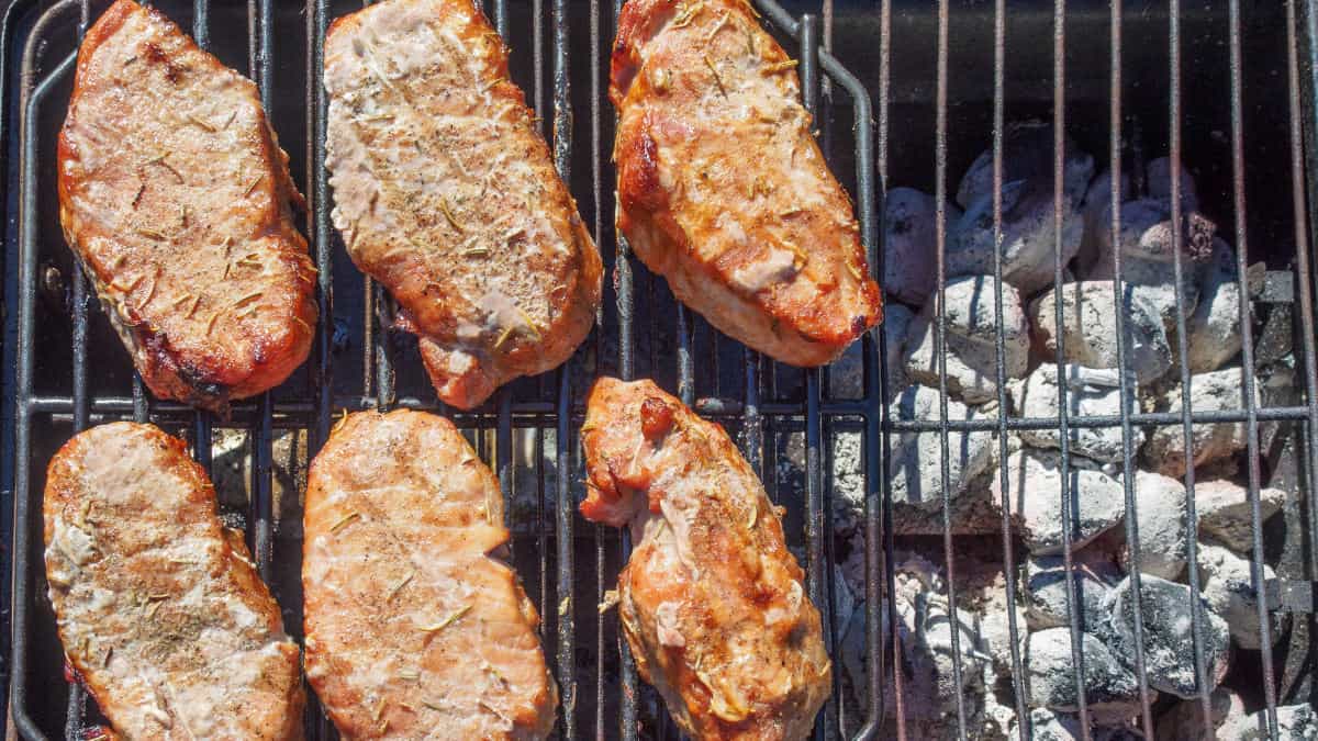 Some small chicken pieces grilling in a two-zone setup on a charcoal grill