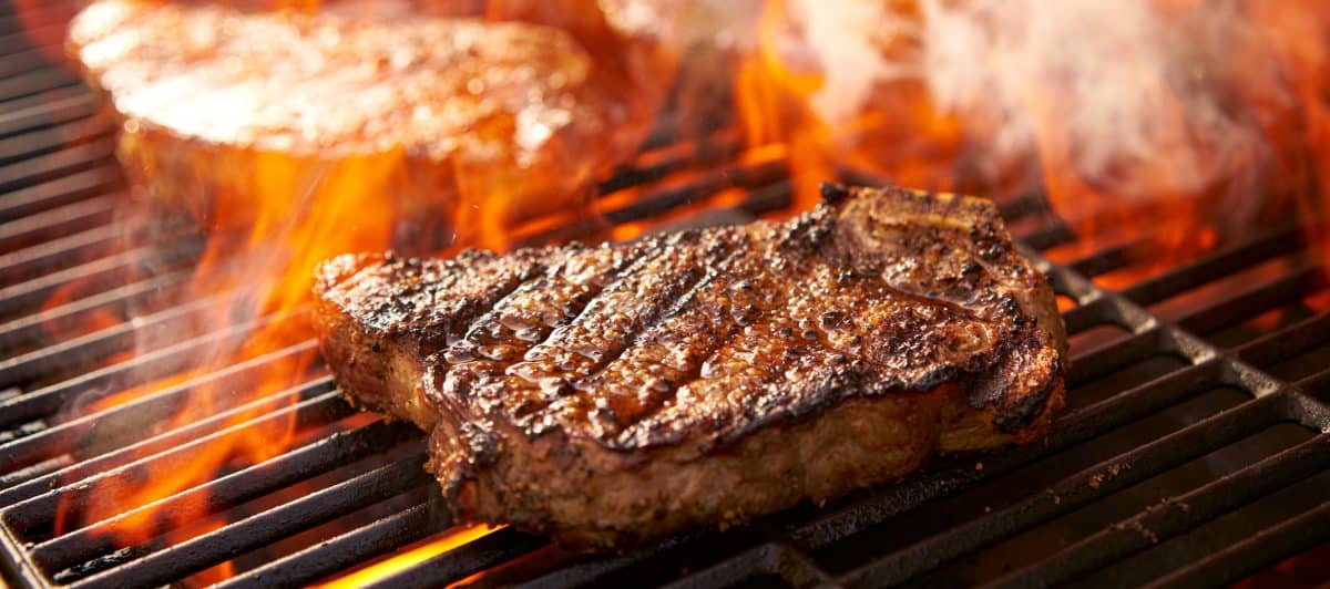 A steak being seared on a fiery hot grill