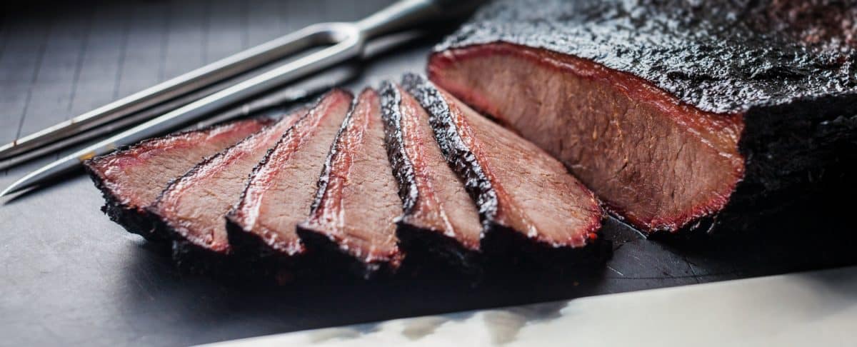 A sliced brisket flat with deep bark and light smoke ring