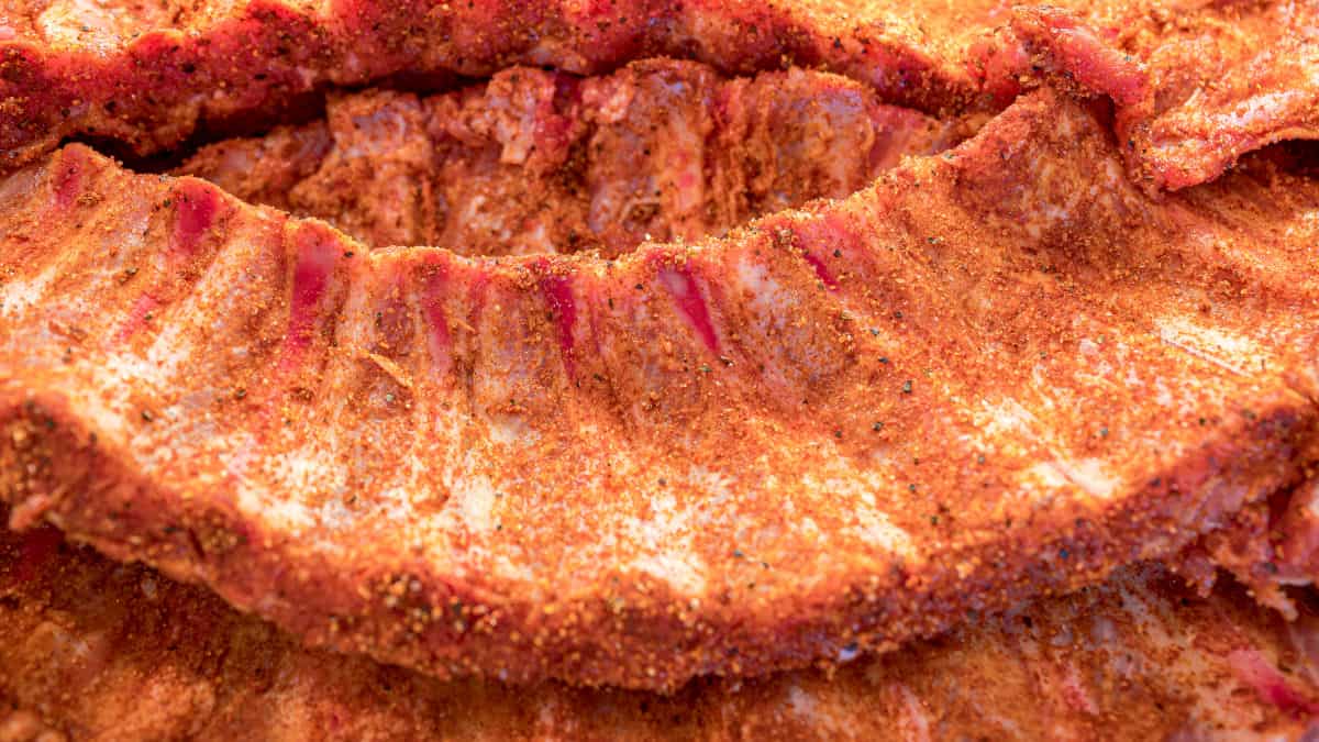 A close up of some pork ribs, with membrane removed and dusted with a red colored dry rub
