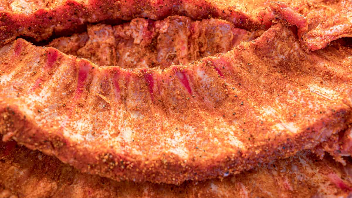 A close up of some pork ribs, with membrane removed and dusted with a red colored dry rub